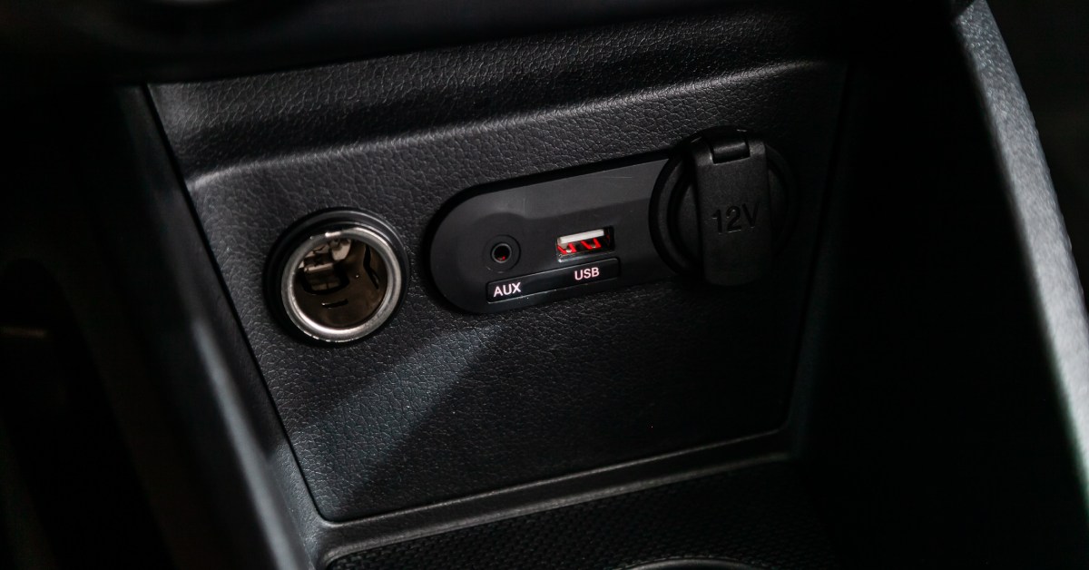 Several in-vehicle electric systems, such as a cigarette lighter, AUX, and USB port, are open on an all-black dash system.