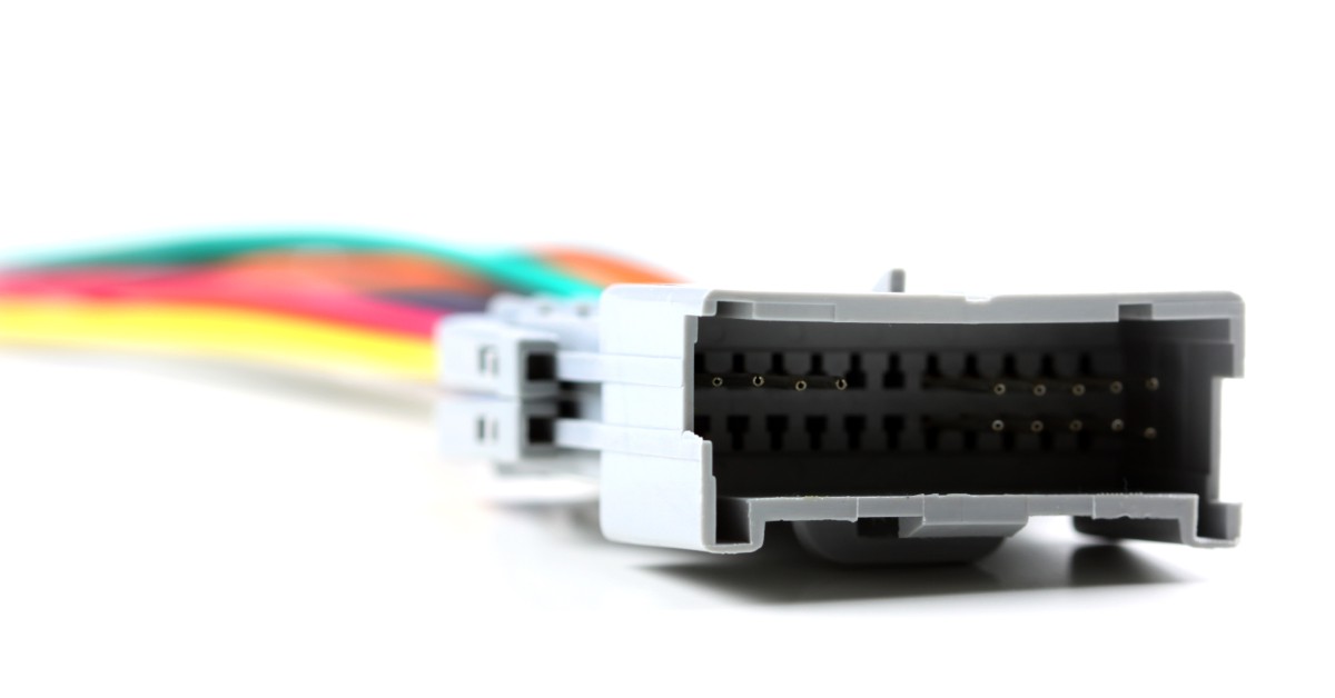 A white, rectangular, 12-pin automotive connector has yellow, red, green, orange and black wires connected to it.