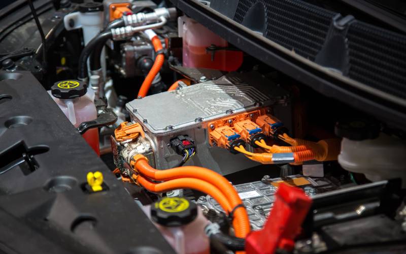 An electric vehicle's engine block. Several large orange cables are coming from the center of the engine.