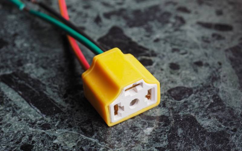 A small yellow electrical connector. It has red, green, and black wires coming out the back of it.