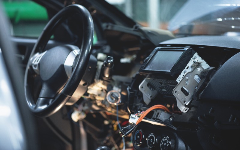  The interior of a car's touchpad system. The dash is open and reveals a large orange wire and connector.