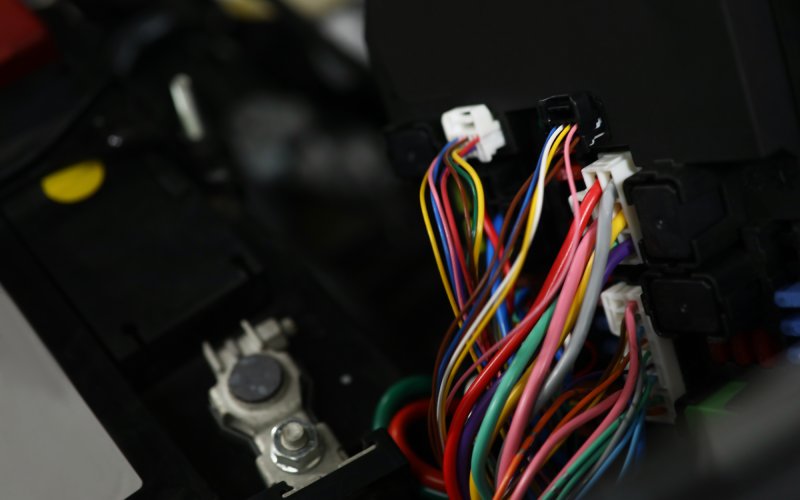 The internal components of a vehicle's touch screen system. A large section of colorful wires all lead to the same connector.