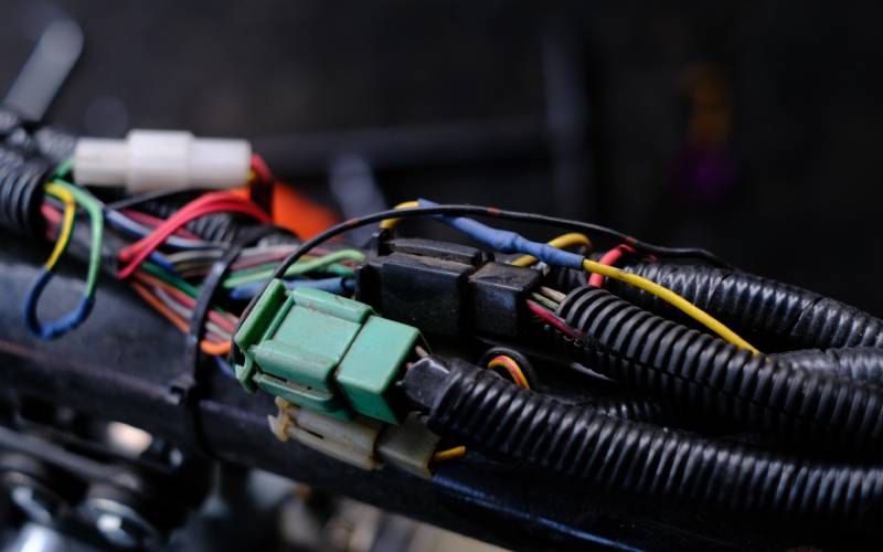 Green connector with colorful wires coming out of it. The wires remained bundled together with a ridged, black casing.