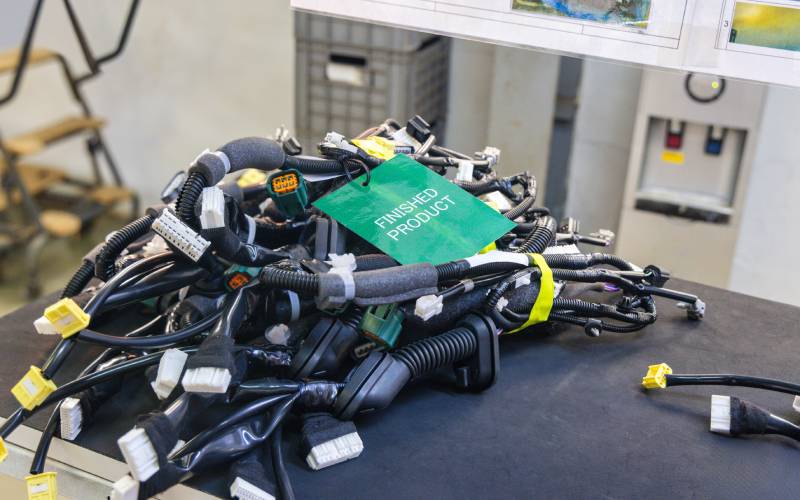 A large pile of bundled wires and connectors sitting on a table. On top of them all is a green tag that reads 'FINISHED PRODUCT'