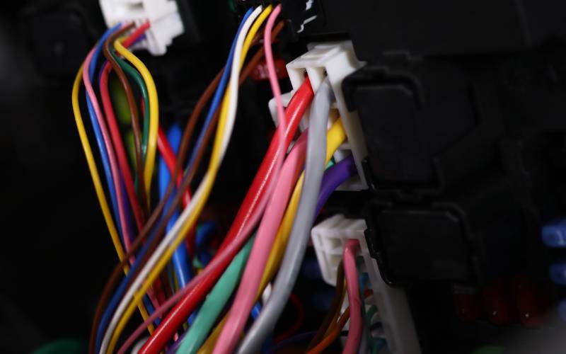 Multiple colored wires plugged into a car's electrical system with white, plastic connectors.