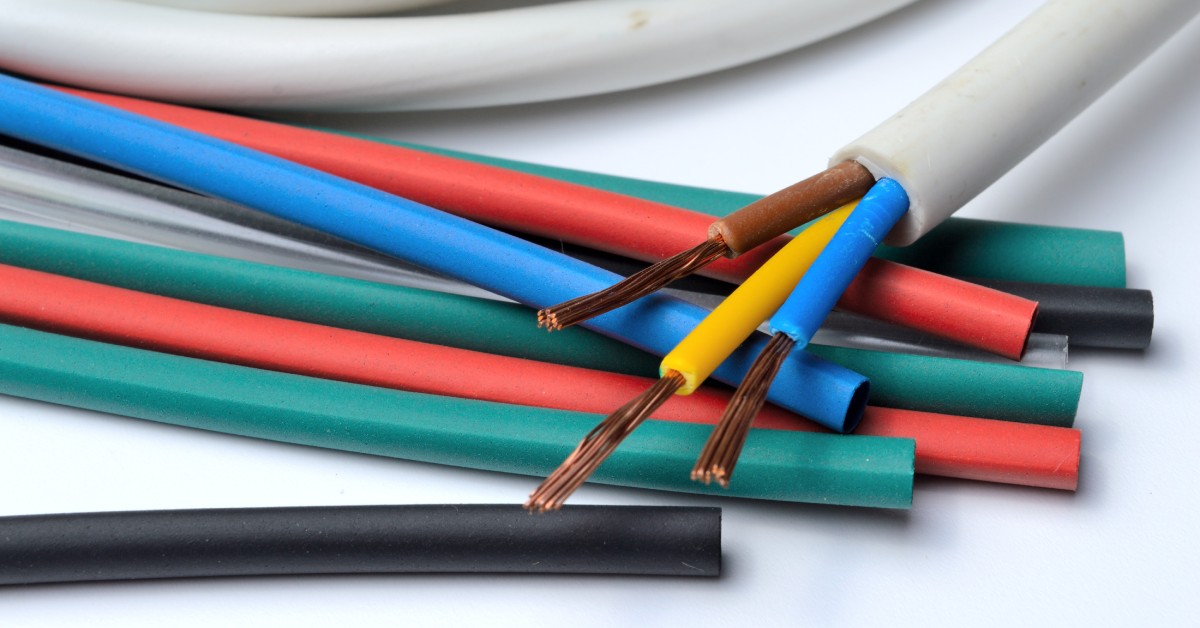 A close-up of various colors of heat shrink tubing and a three-core stripped wire on a white background.