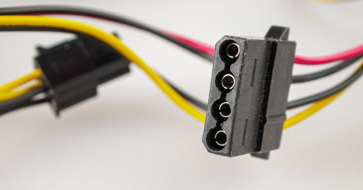 A black four-pin connector attached to yellow, black, and red wires. The connector is on a white table.