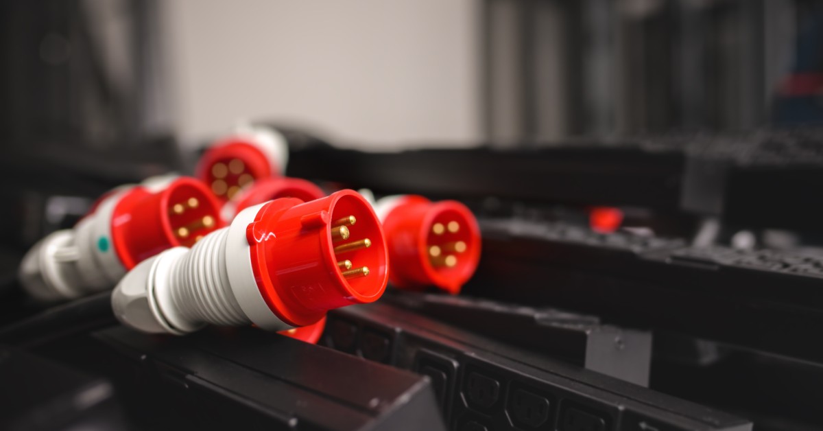 Five red-and-white five-pin connectors inside a large room. The connectors are surrounded by black electrical rails.