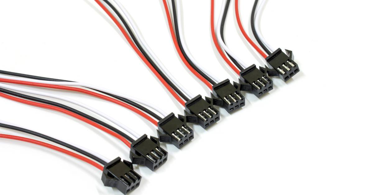 Seven small, black 3-pin connectors lay in an organized row. Each component has a white, black and red wire connected to it.