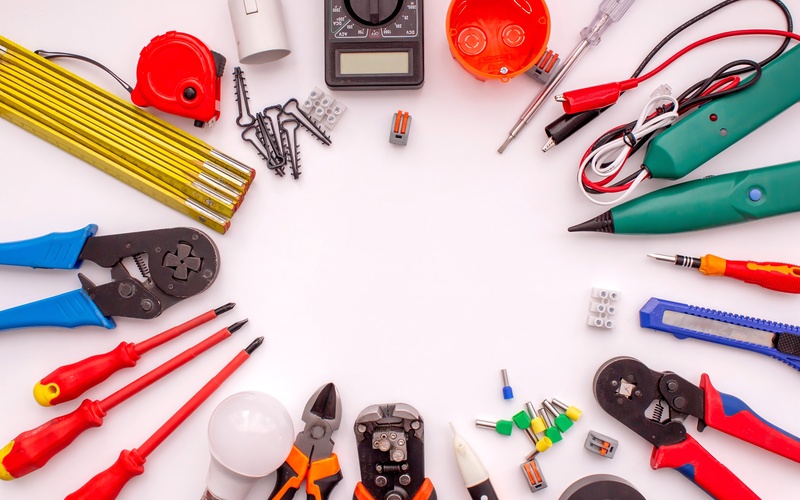 Electrical tools like electrical testers, wire cutters, and electrical tape arranged in a circle on a white background.