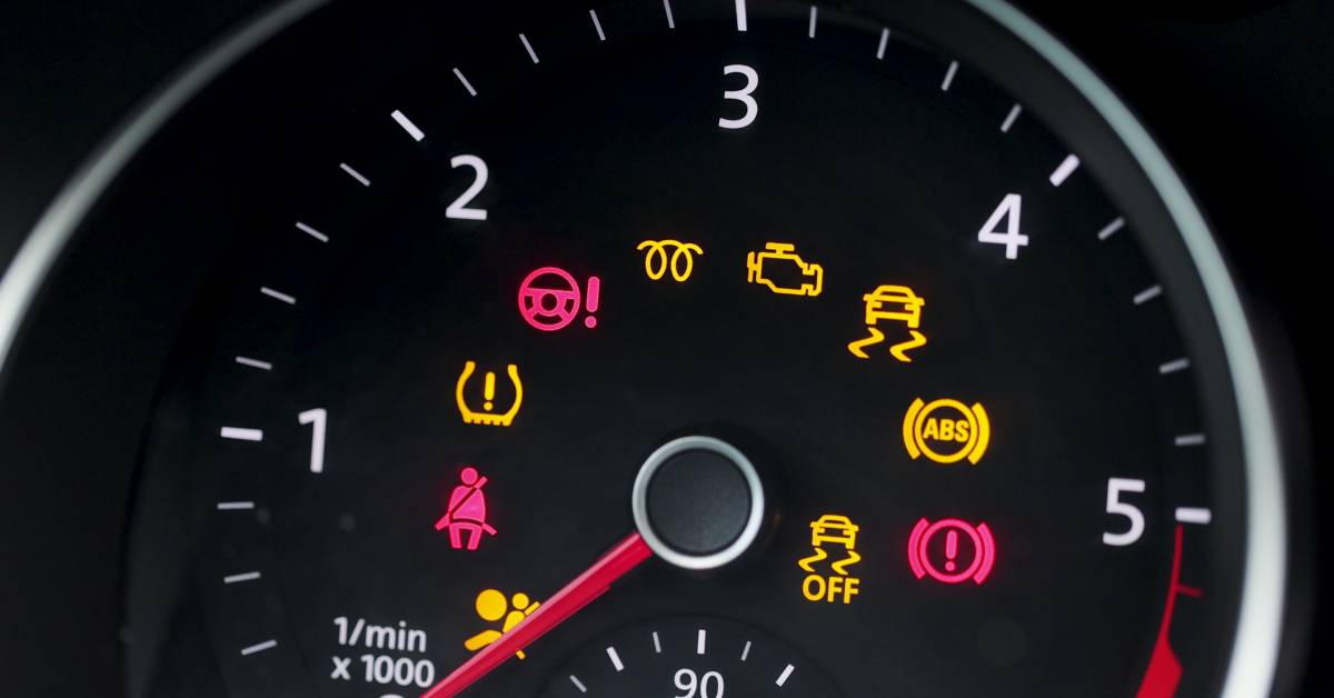 A vehicle’s dashboard with the warning lights illuminated for systems including the seatbelts, brakes, and engine.