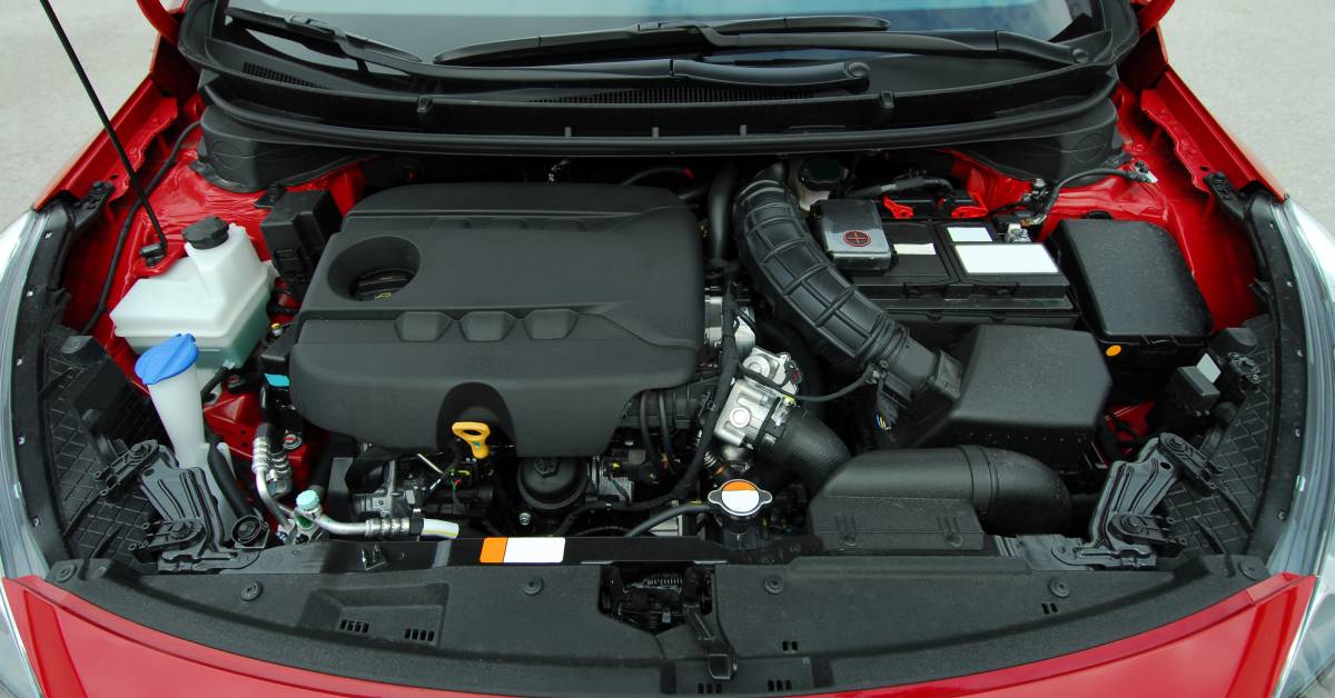 A red car with the hood lifted for a close inspection of the components under the hood that require electrical connectors.